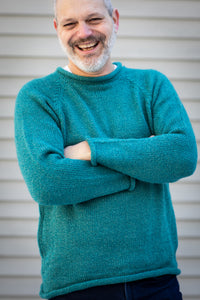 Michael wearing a size XL teal fisherman sweater with arms crossed against a neutral background