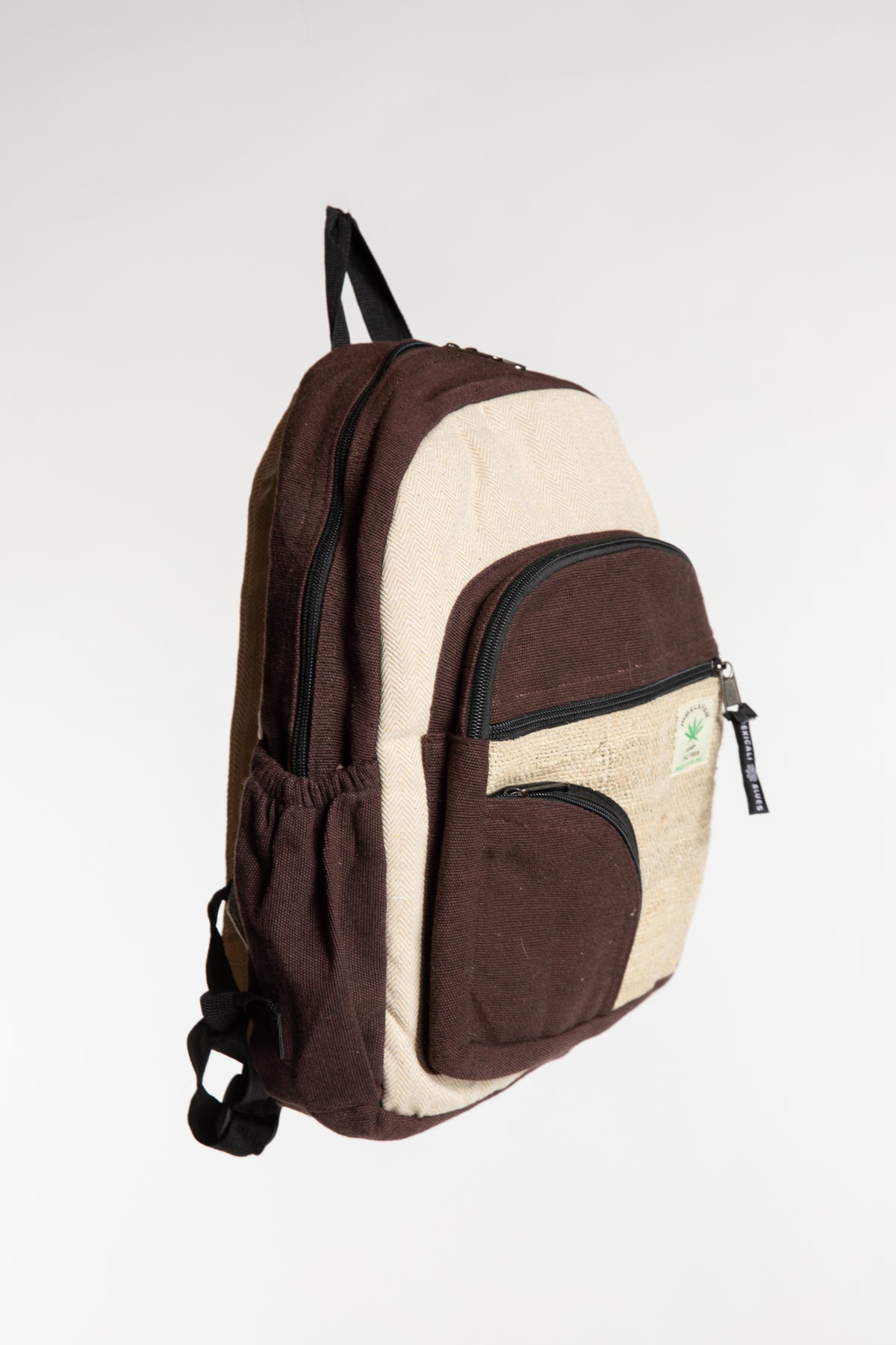 Side view of brown hemp backpack with contrasting cream panels and adjustable straps