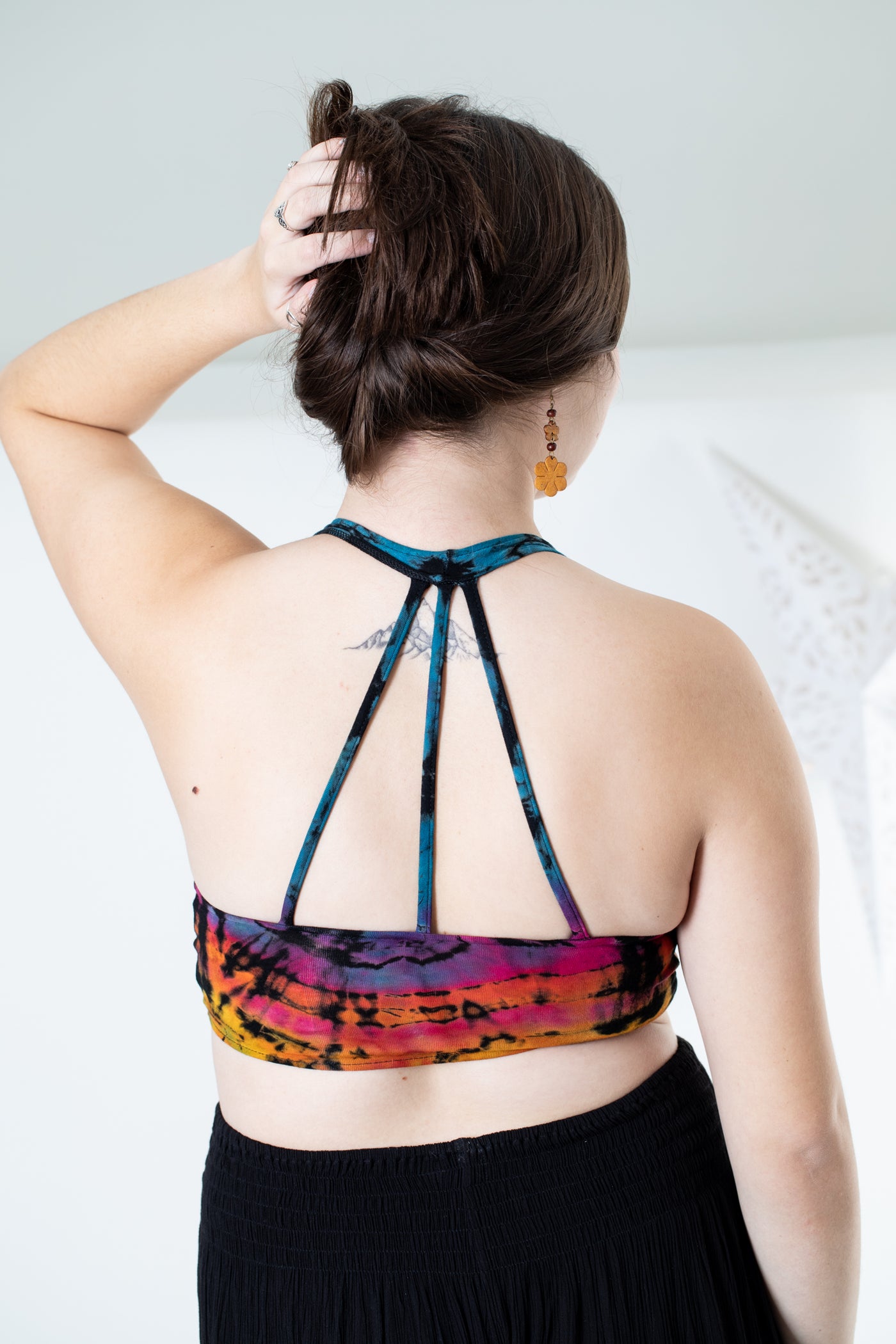 Gabby is wearing a tie dye wrap top in black rainbow 