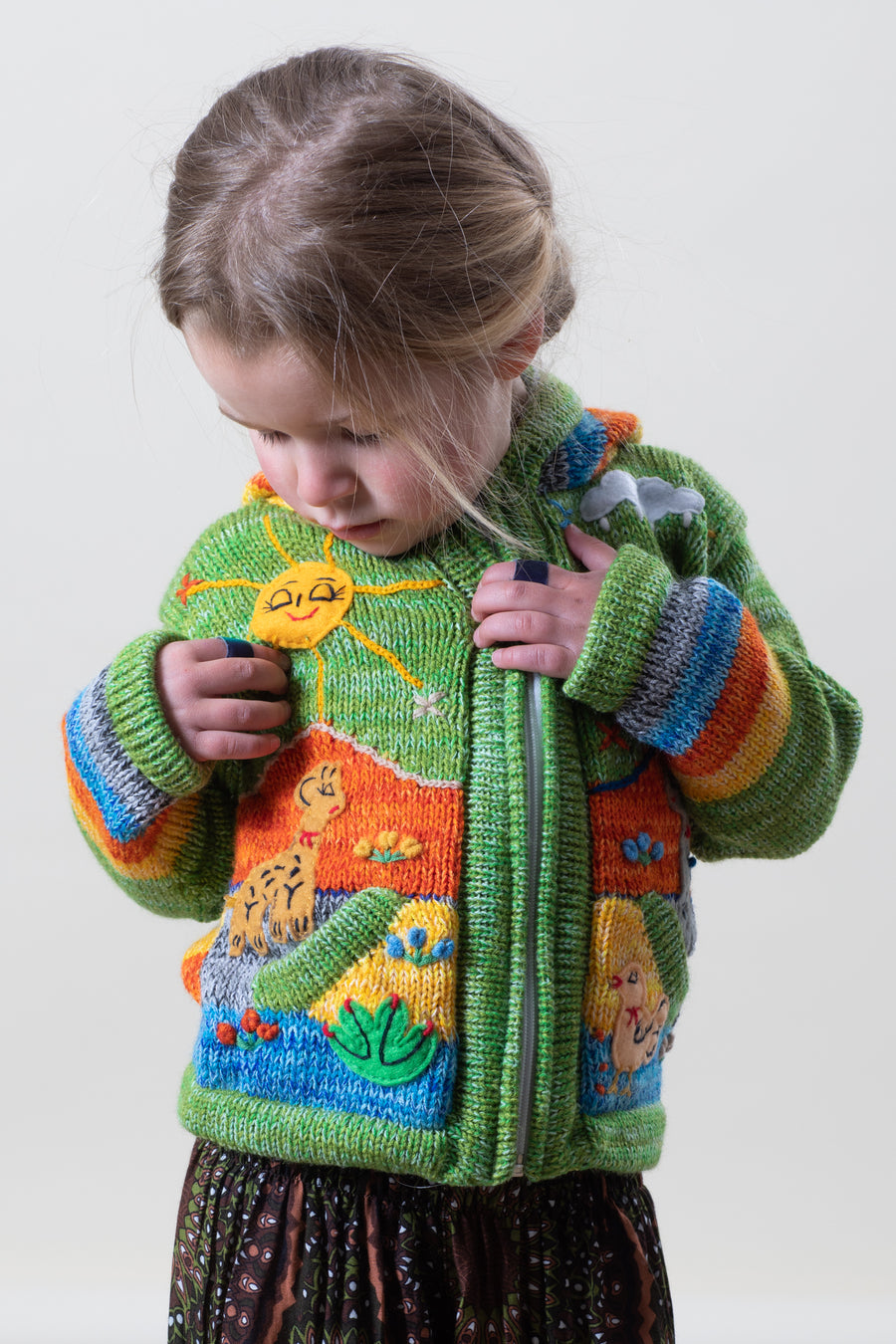 Poppy is wearing a kids nature scene sweater in green