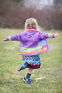 Poppy is wearing a kids nature scene sweater in lavender